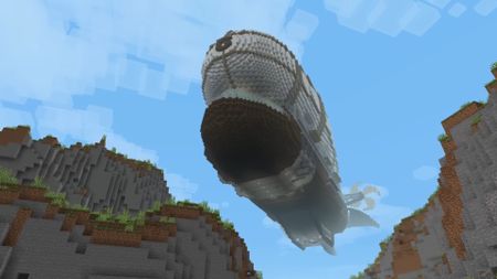 Viewed from below, an airship glides through a valley in Minecraft