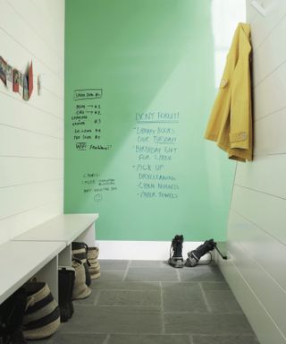 mudroom with green wall with writing, benches with storage baskets and coat hooks -Benjamin Moore