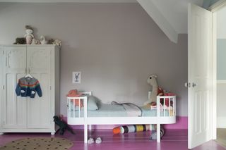 girls bedroom with grey walls, freestanding wardrobe, toddler bed, bright pink floor and skirtings