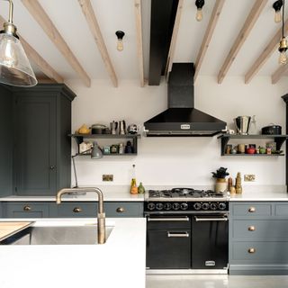 kitchen with white wall grey cabinet wooden beams on ceiling and chimney