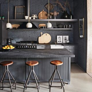 Kitchen with dark grey walls and kitchen island with bar stools