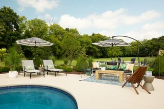 pool landscaping ideas: outdoor living space at the end of a backyard pool