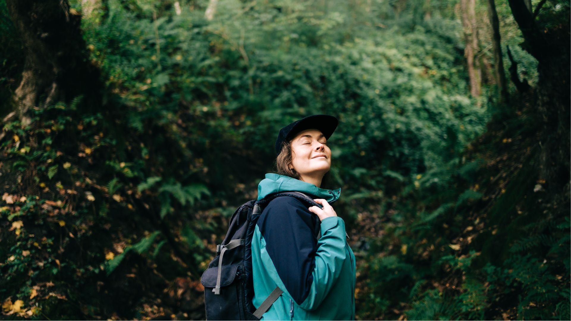 Woman looking up and smiling at trees while out hiking
