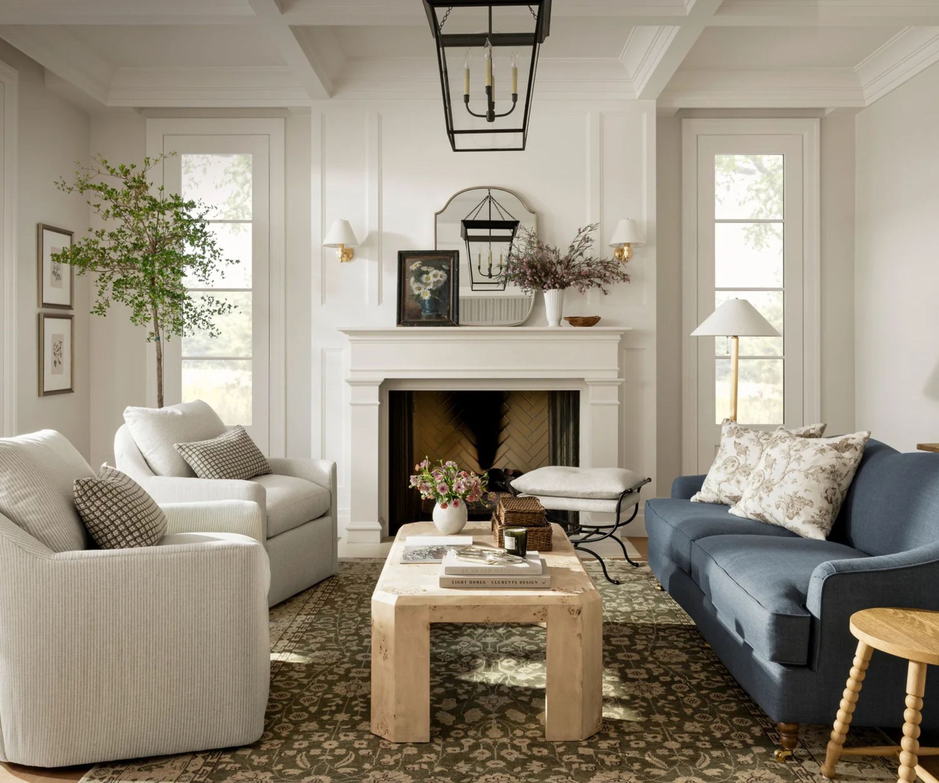 mcgee and co white coastal farmhouse summer living room with two white striped armchairs, a light navy couch, large vintage style rug and wooden table and little decorative bobbin stool