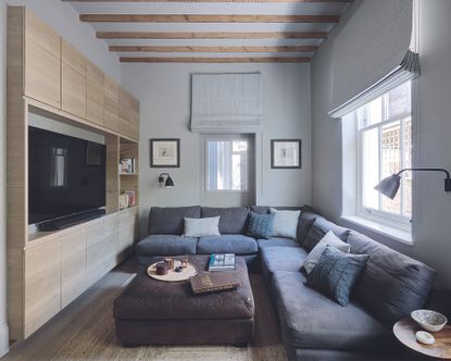 a corner sofa in a living room with a TV and wall units