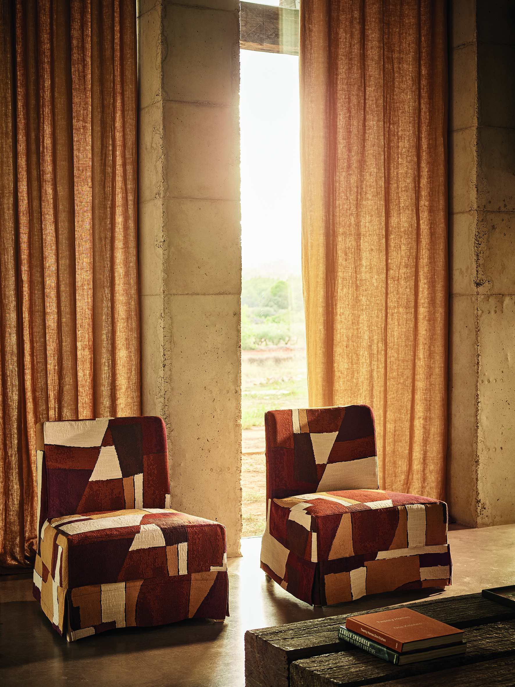 two patterned upholstered chairs in front of a brown linen curtain