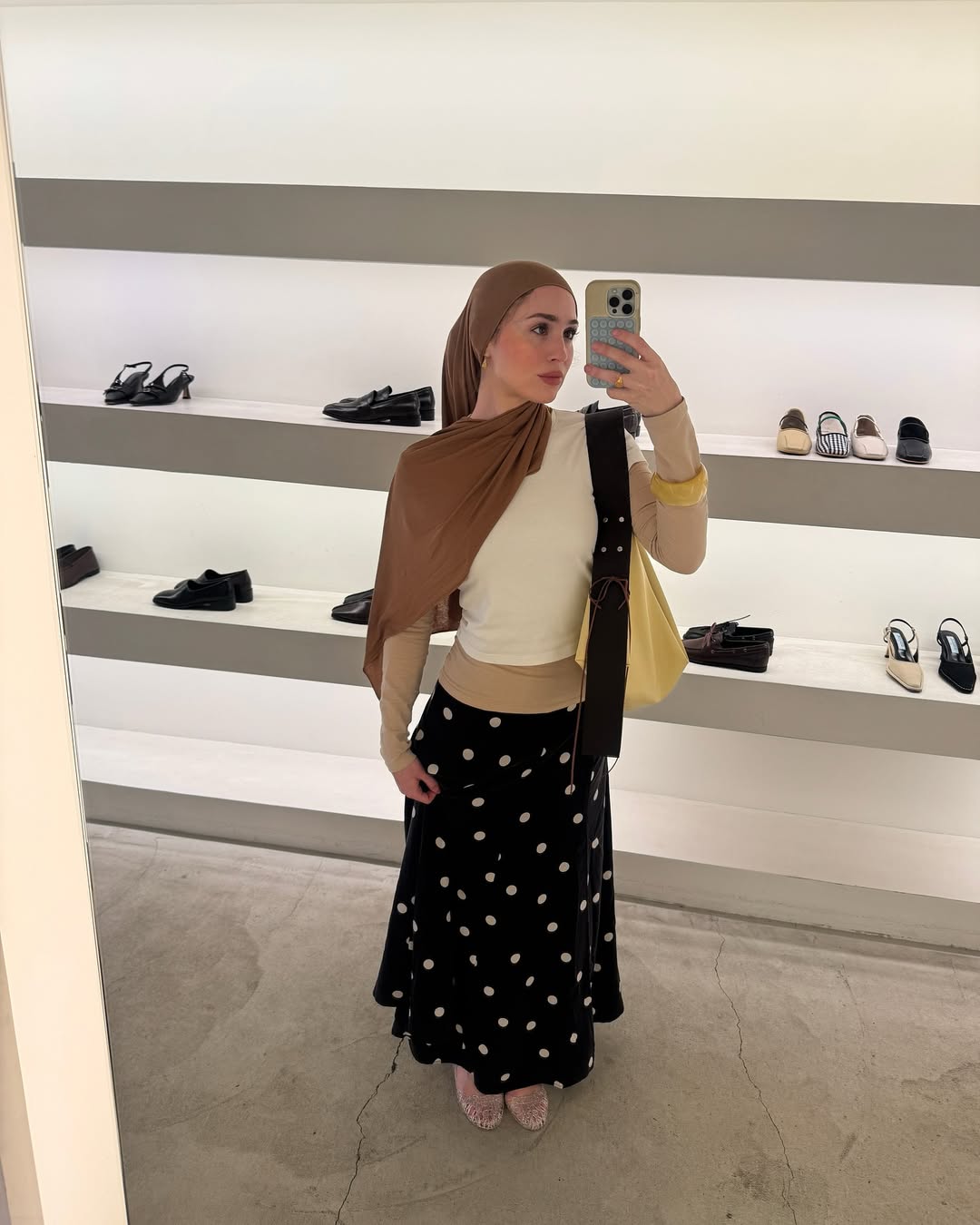 @mariaalia weats a black-and-white polka dot skirt with a white and cream top, yellow bag and mesh flats