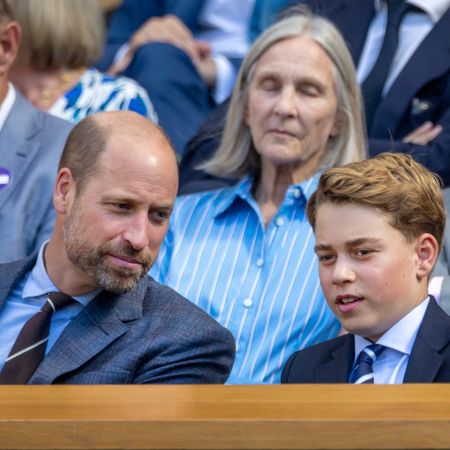 Prince William has a bald head and wears a suit while smiling at son Prince George as the pair attend Wimbledon 2026