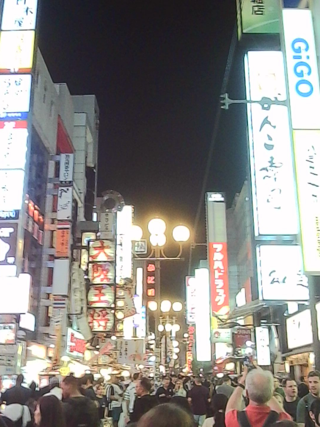 Busy Japanese street at night filled with illuminated signs and crowds.