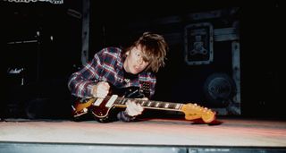 Thurston Moore, pictured in 1990, lies on the stage and plays a Jazzmasters with Sonic Youth