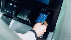 A credit card being inserted into an ATM. 