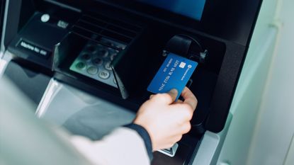A credit card being inserted into an ATM. 