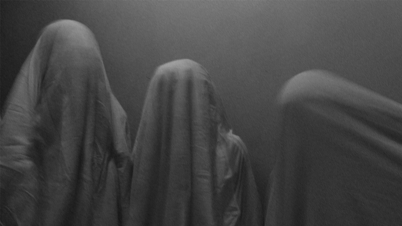 A black and white photo of Qasu dressed in black sheets