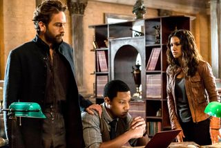 Tom Mison, Jerry MacKinnon, Janina Gavankar look over a document in a spooky office in a still from the show sleepy hollow