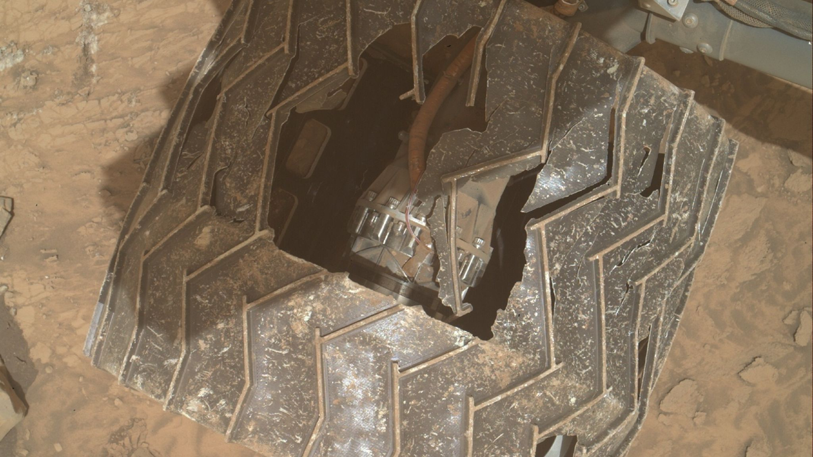 A photo of one of the Curiosity rover's wheels with a large hole revealing an inner mechanism