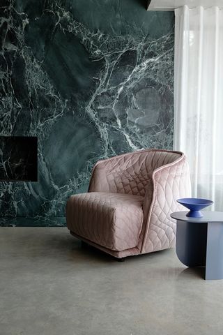 living room with marble wall and cream armchair