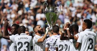 Real Madrid's French forward Karim Benzema (C) and teammates hold the European Champion Clubs' Cup trophy, awarded for winning the UEFA Champions League, on the pitch before the start of the Spanish league football match between Real Madrid CF and Real Betis at the Santiago Bernabeu stadium in Madrid on September 3, 2022.