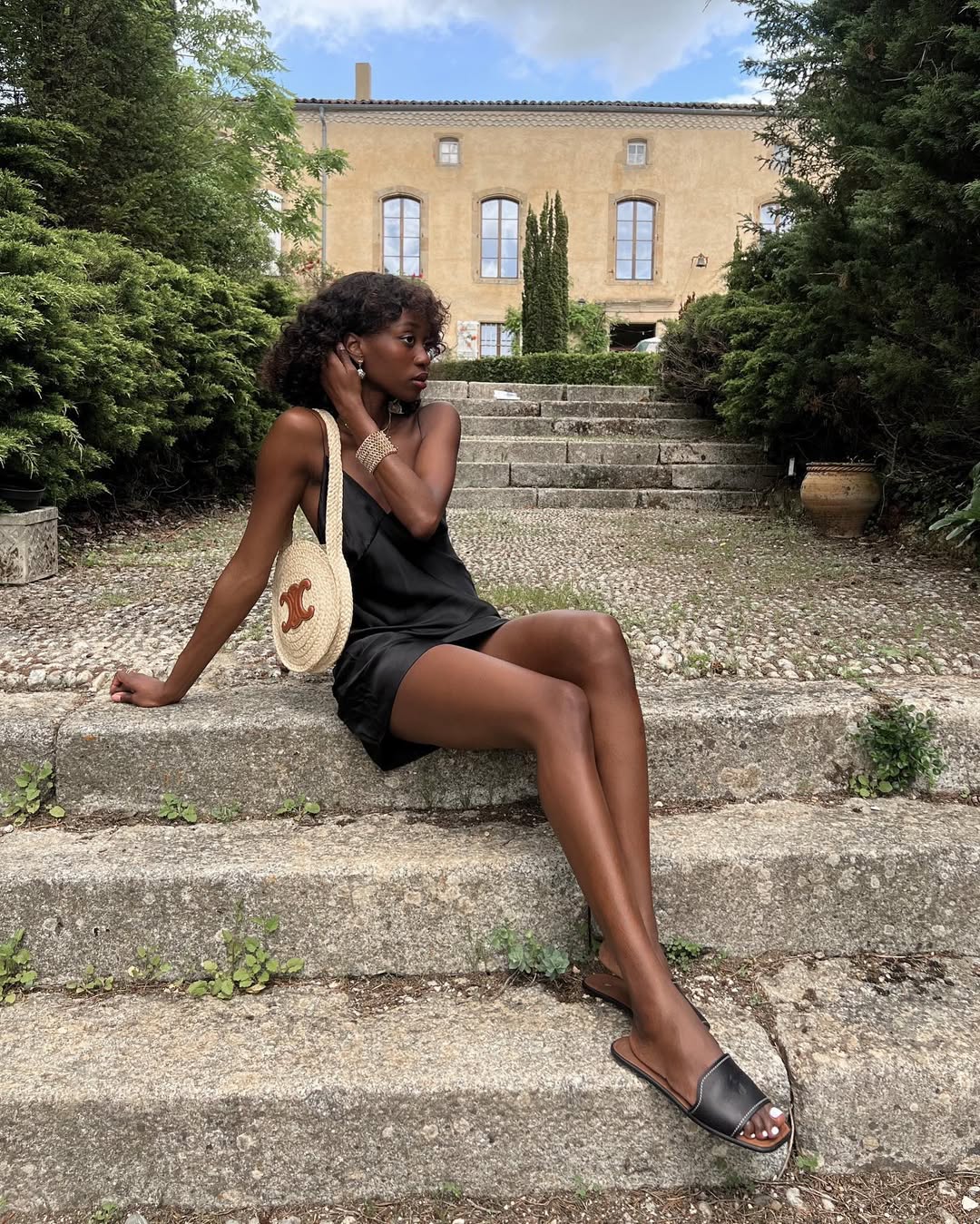 @emmanuellek_ wears a black mini slip dress with slides