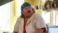 Stavros Halkias in a dirty white chef coat and blue bandana in Tony