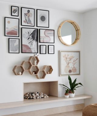 Mix of modern art on a gallery wall with hexagonal shelving and a wicker lined mirror