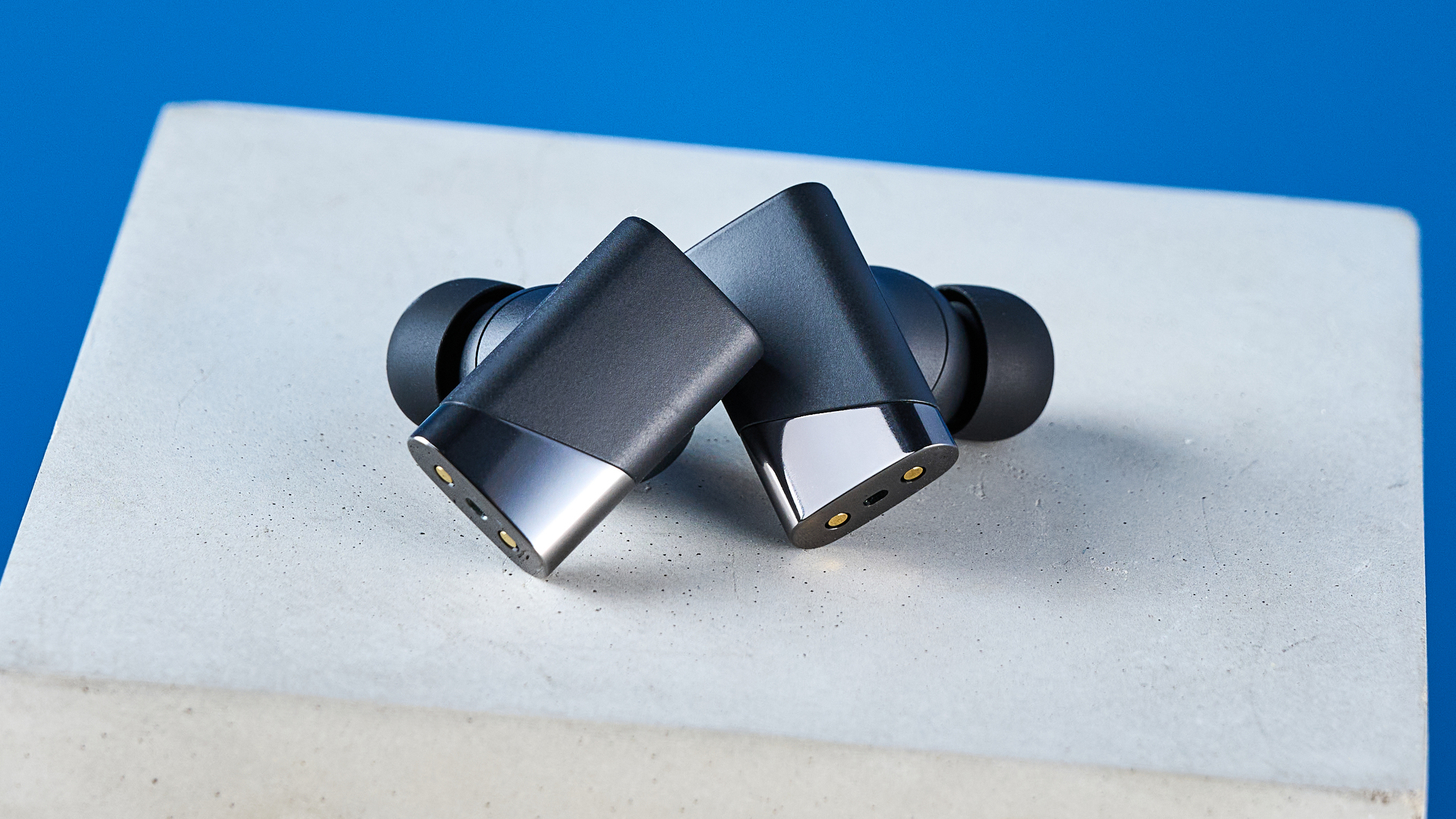 A pair of black Status Pro X wireless earbuds