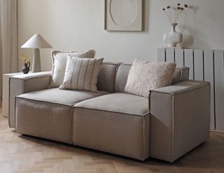 a beige sofa with offset pillow arrangement