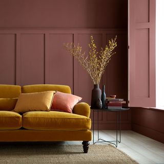 Living room with mustard sofa and burgundy wall paneling