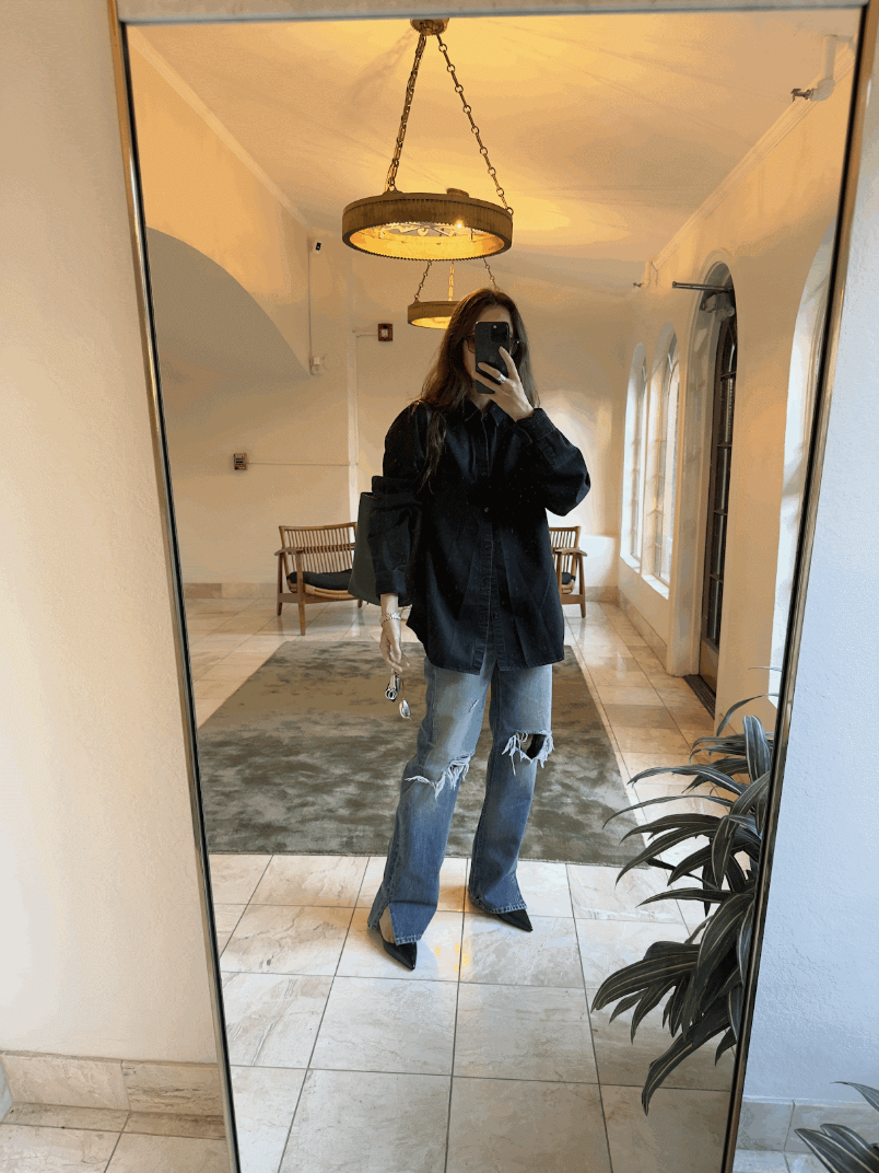 Rachel Whitehouse posing in mirror wearing black button down and ripped jeans