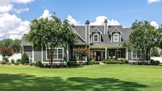 A large gray craftsman house with a large green front lawn