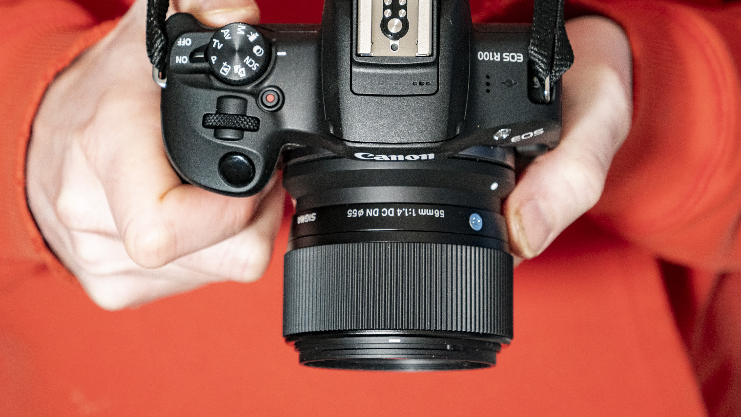 Sigma 56mm F1.4 DC DN Contemporary lens in the hand attached to a Canon EOS R100