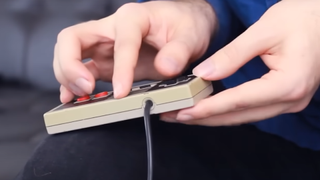 An image of aGameScout demonstrating the rolling technique, placing their thumb on a d-pad of an NES controller and rolling their fingers along its spine.