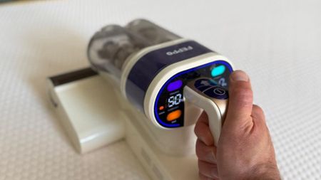 The image shows a male hand holding the handle of a FEPPO mattress cleaning, while running along the surface of a white mattress