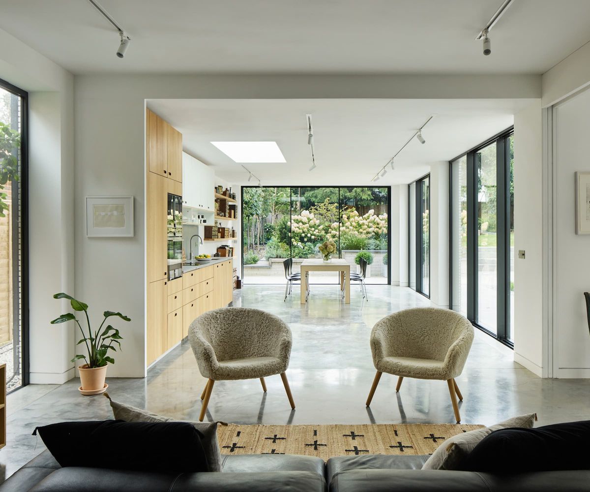 A separate open plan kitchen with brown cabinets and leading to bifold doors into the garden
