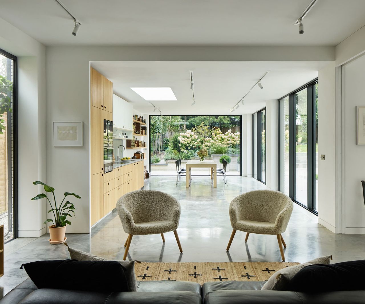 A separate open plan kitchen with brown cabinets and leading to bifold doors into the garden