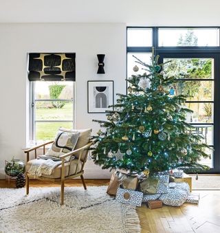 christmas tree and presents in living room with white walls and white rug