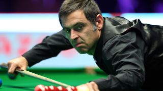 Ronnie O'Sullivan of England leans over the green baize to play a shot during the Masters snooker 2024