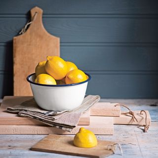 Lemon in white bowl infront of wooden board