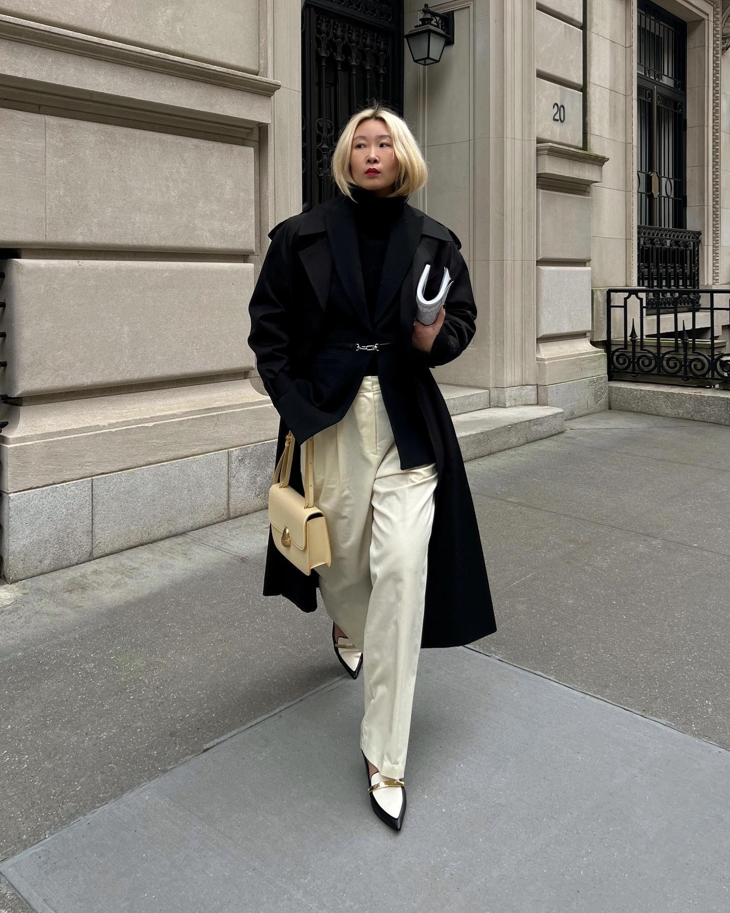 A woman posing on the street in a chic monochrome outfit with an ashy blonde bob