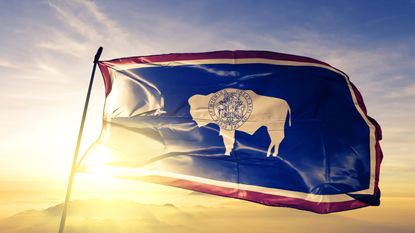 Wyoming flag blowing the wind during sunrise for a Wyoming state tax article