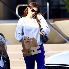 Kaia Gerber wears a gray sweatshirt, blue straight leg jeans, a black bag, and birkenstock boston clogs