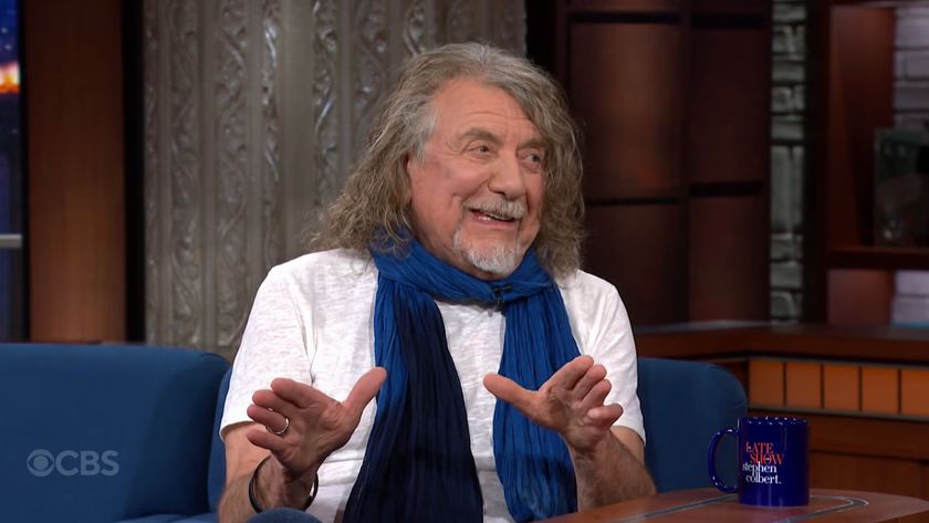 Robert Plant smiling in a white shirt and a blue scarf