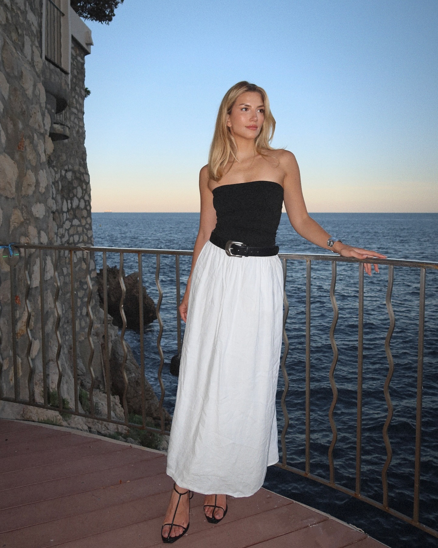 French woman wearing white maxi skirt, black tube top, skirt and black heels.