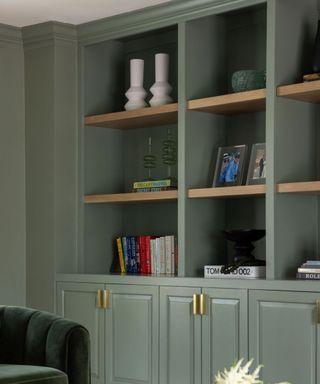 A light green built-in bookshelf styled with family photos, books, and decorative items