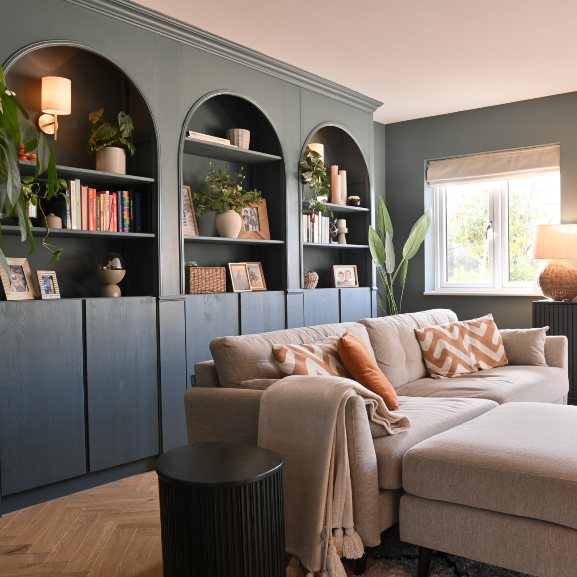 blue living room with custom built and arched storage, L shaped beige sofa, parquet flooring