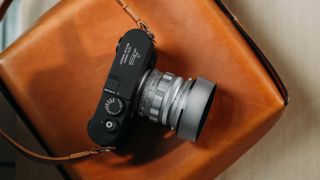 The new Leica M11-D on top of a leather bag with a silver lens attached