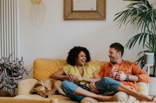 Woman and man sitting at home on the sofa, laughing