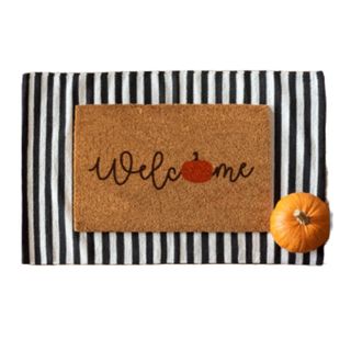 Pumpkin door mat with striped mat underneath and pumpkin in corner
