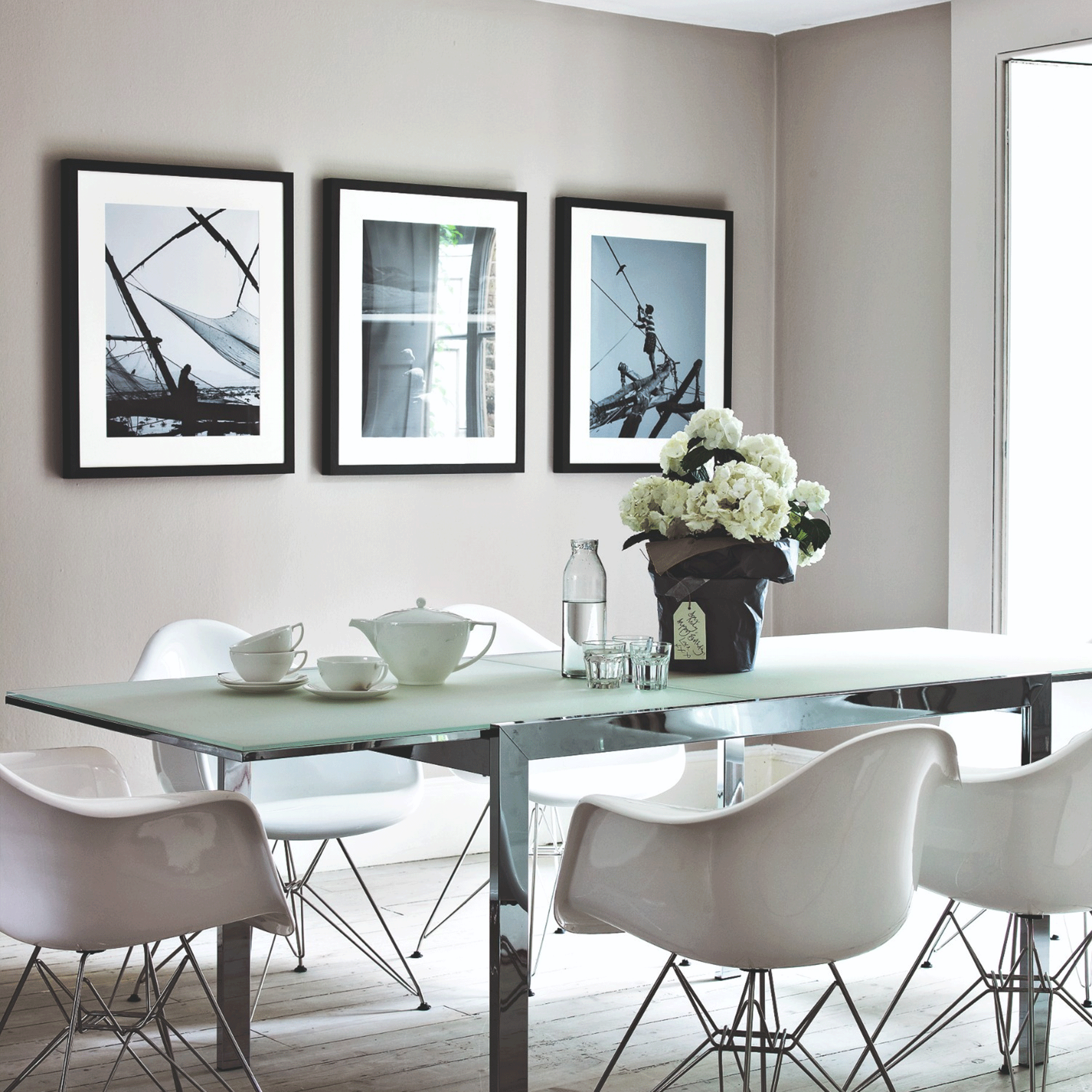 Grey living room with three pictures and glass table