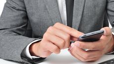 A man in a suit tapping the screen of a mobile phone