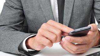 A man in a suit tapping the screen of a mobile phone